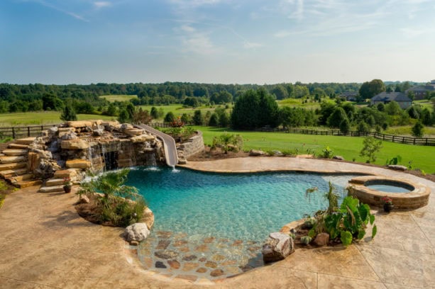 a rustic backyard featuring a custom-shaped pool and stamped concrete around