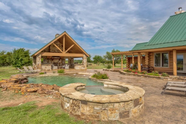 mountain style backyard area with stamped and stained concrete around a pool