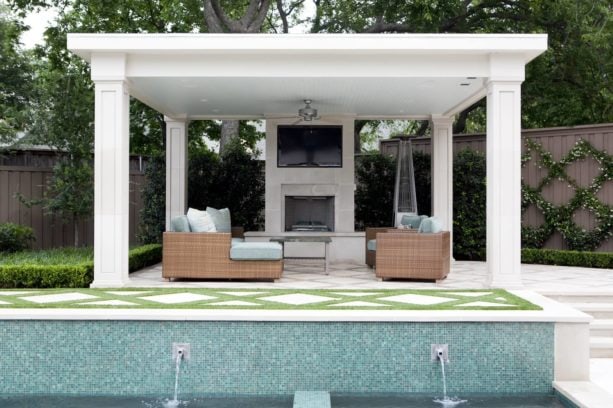 outdoor living room with square white columns and tv above a fireplace