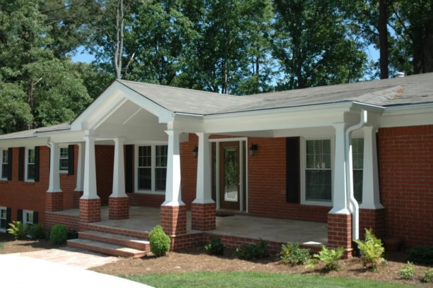 large front porch of a ranch style home with gabled ceiling and multi-tapered columns