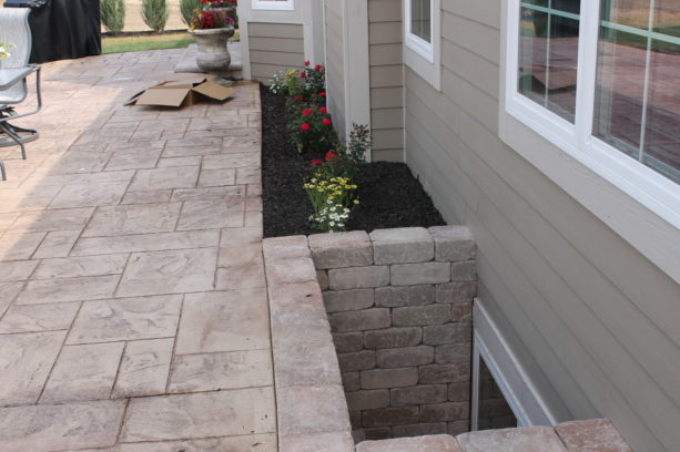 stamped concrete basement window wells in a backyard patio