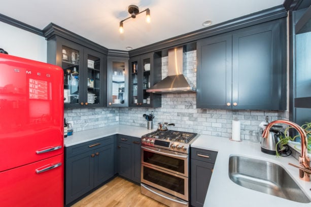 a transitional kitchen decorated with black cabinets and red retro fridge