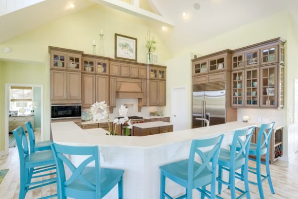 bright blue colored chairs combined with white backsplash and brown glass-front cabinets to add a coastal look in the kitchen