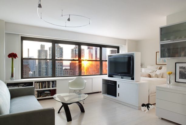 simple tv stands as a room divider to separate the bedroom and the living room in a studio apartment