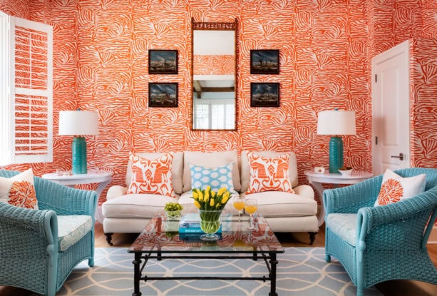 vibrant patterned orange wall combined with cyan blue accent chairs in a tropical living room