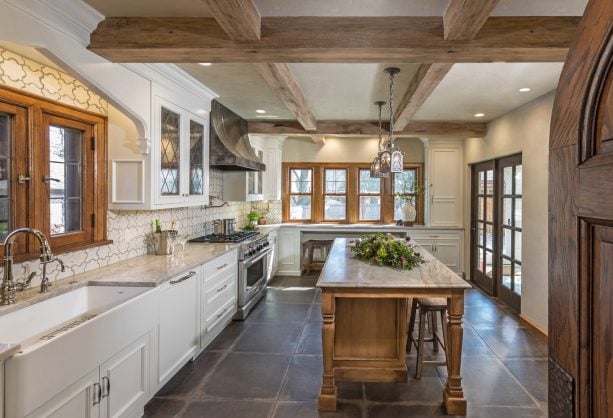 gray porcelain tile kitchen floor with white cabinets and medium tone wood island