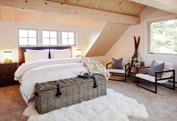 rustic attic bedroom with vaulted ceiling and slanted walls in a natural wood finish