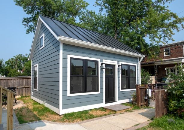 black metal roof with soft green siding color scheme