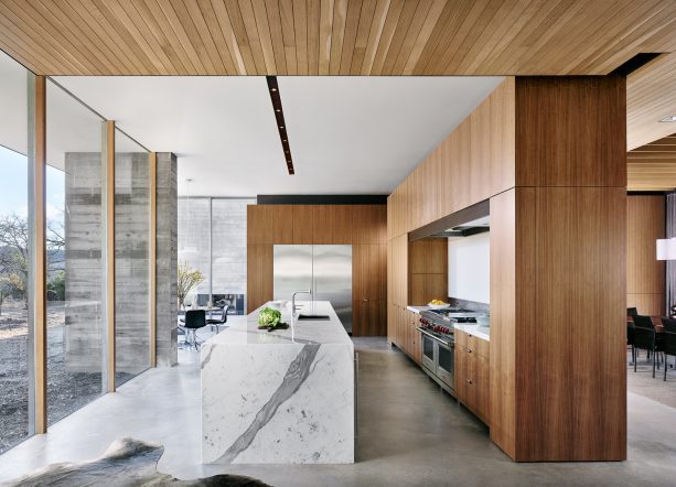 gray concrete kitchen floor with walnut cabinets and white marble island