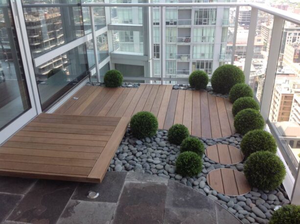 landscaped balcony flooring idea with hardwood decking, rocks, and stone