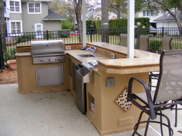 classic l-shaped outdoor stucco finished kitchen completed with bar seating area