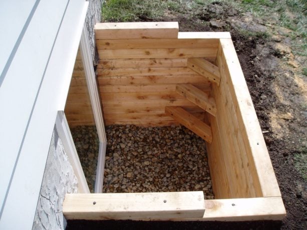 light tone wood basement window well with tiny steps in the corner