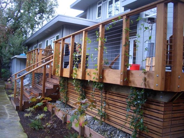 narrow under deck landscaping with river rocks and bordered by a wooden board