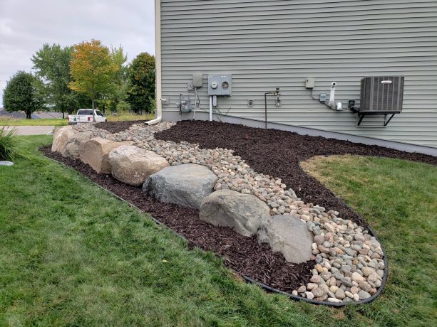 rock garden as dry creek drainage designed with natural boulders