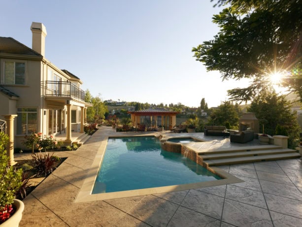 an extensive stamped concrete pool deck with a raised hot tub