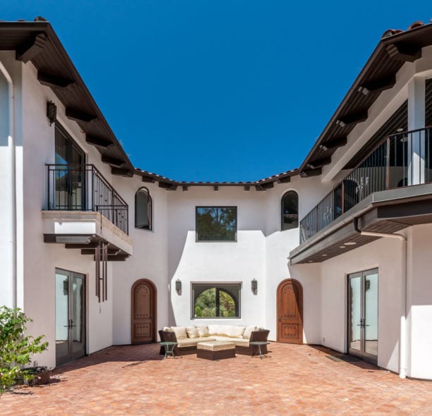 u-shaped courtyard surrounded by spanish style balconies in a white exterior home