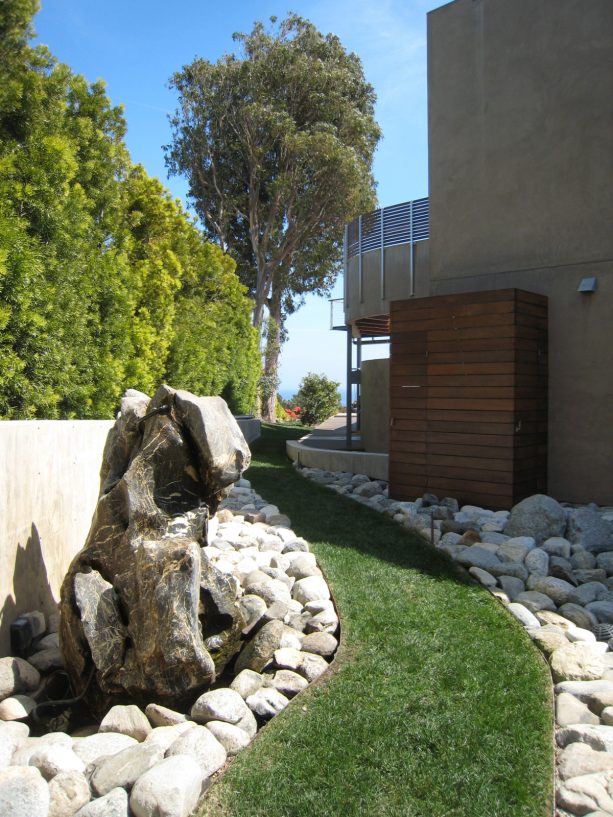 big rock garden completed with a water feature to border the lush green grass