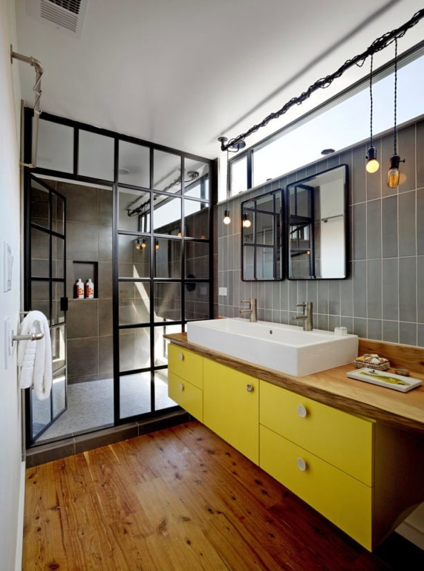 the combination of grey, yellow, black, and wood colors in an industrial bathroom