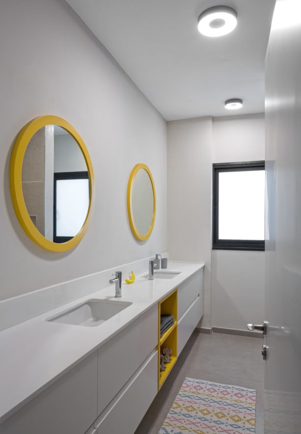 a grey contemporary bathroom with two round yellow wall mirrors