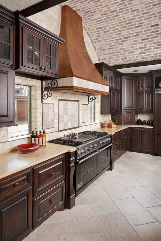 dark raised panel cabinets with light beige granite countertops that match the backsplash and floor