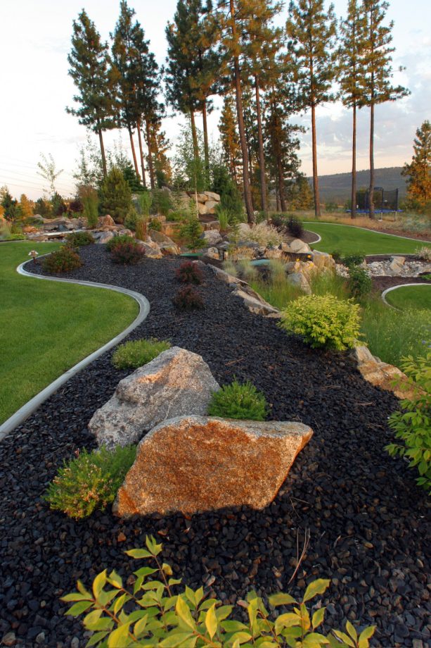 dark colored basalt rock as a backdrop for large decorative granite boulders