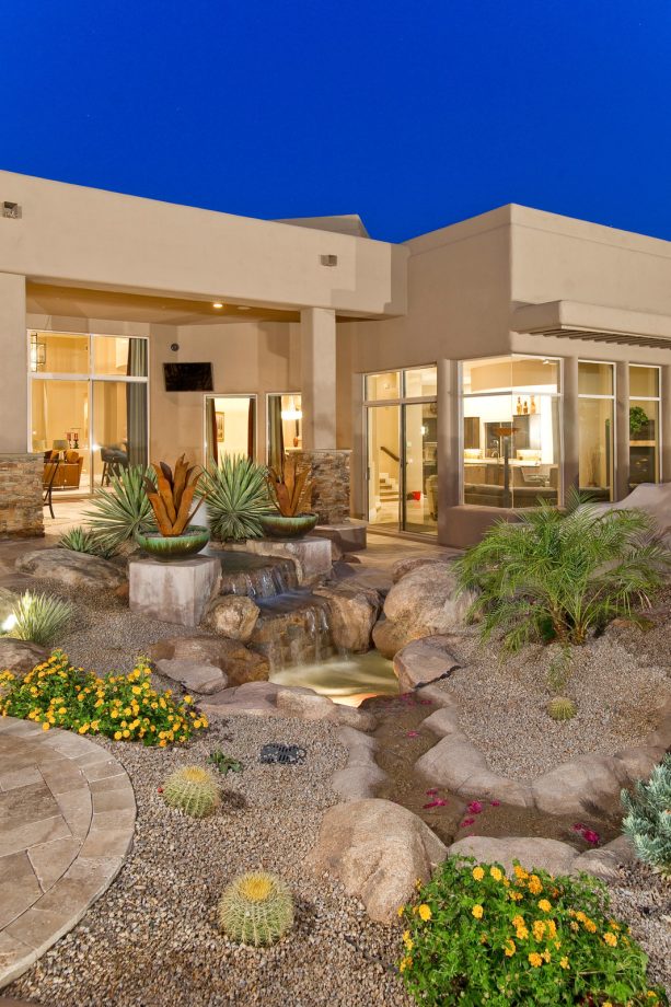 water fountain landscaping in beige color with boulder walls and small rock cover