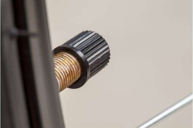 Extreme closeup of a Schrader valve on a bicycle wheel rim