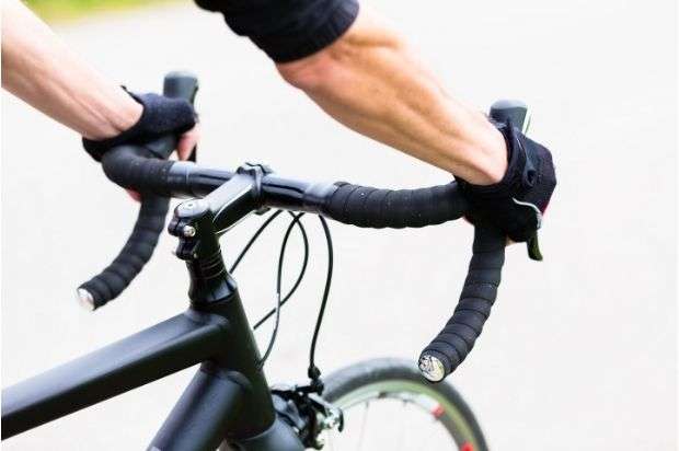 Side view of a cyclists arms holding drop handlebars