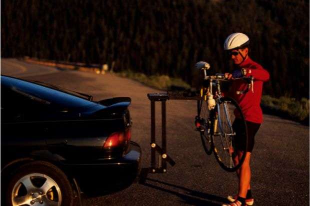 Man loading bike onto bike rack after learning how to fit a bike in a car