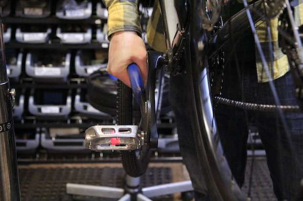 Mechanic works to get pedals off a bike