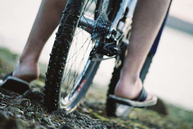 Close up of feet reaching to the ground on either side of a bike