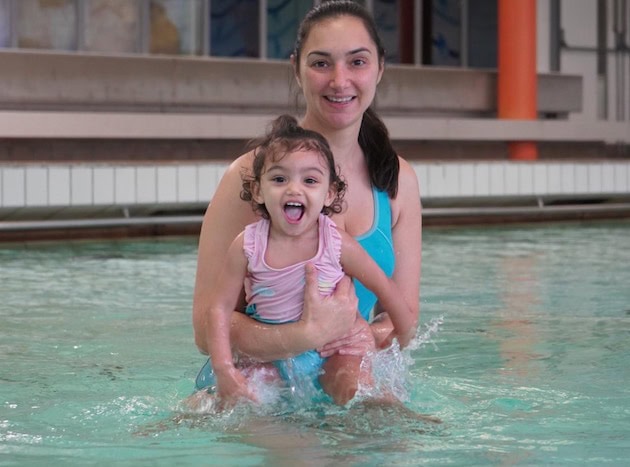 a toddler with her mum in swimming pool during a Blue Wave Swim School's swimming lesson at Putney leisure centre, in southwest London