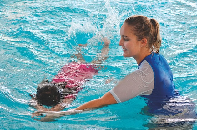 Specialized ASD swimming instructor teaching a child