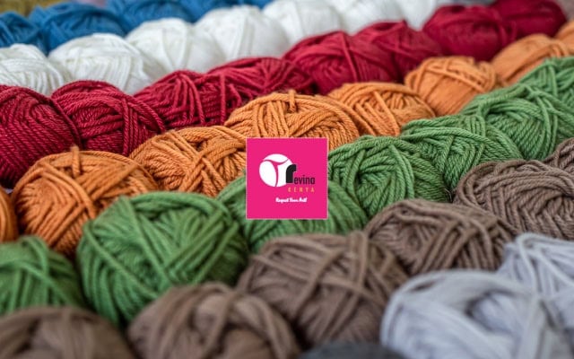 Close-up of colorful yarn balls arranged in rows with a pink logo card in the center.