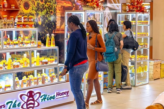 Shoppers browsing illuminated honey displays inside a retail shop