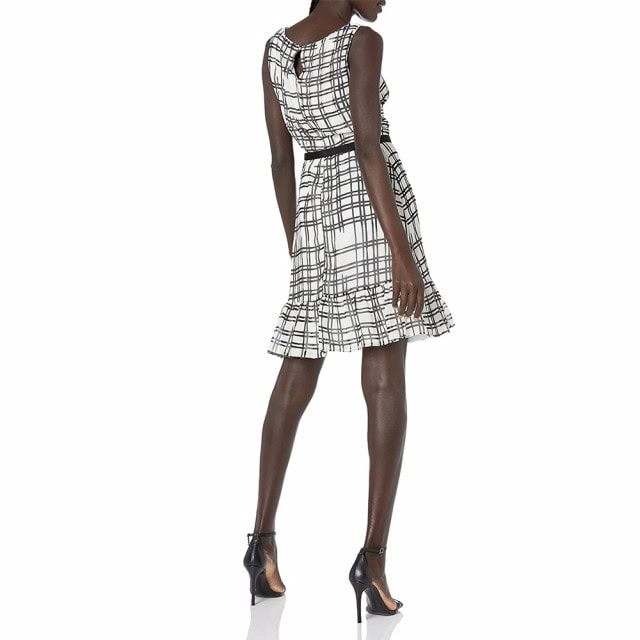 Model wearing a sleeveless black-and-white plaid dress with black ankle-strap heels
