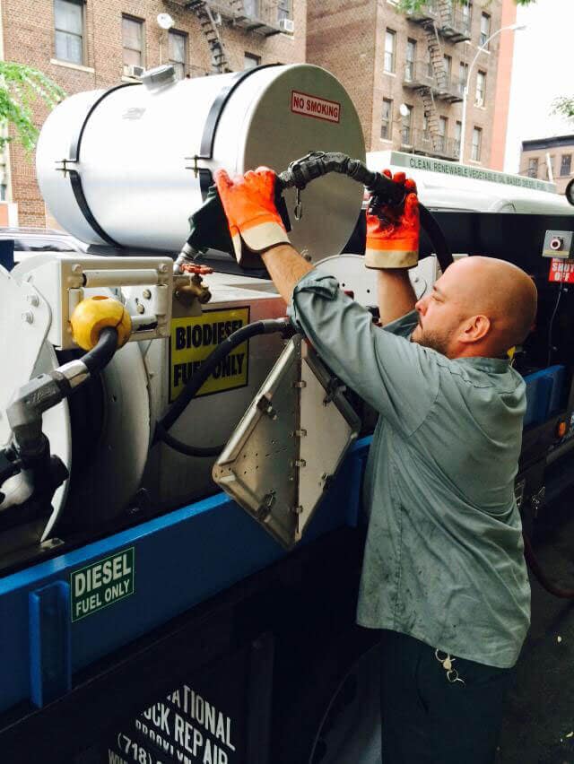 One worker on a set fills an on-site power generator with biodiesel fuel, which is cleaner diesel.