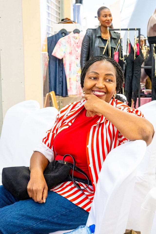 A smiling guest in a red-and-white striped jacket enjoys Style, Shop & Sip.