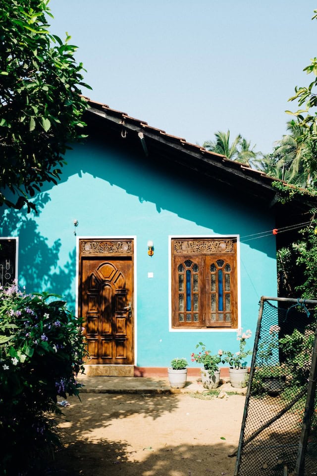 cyan coloured single floor house front with clay tile sloping roof