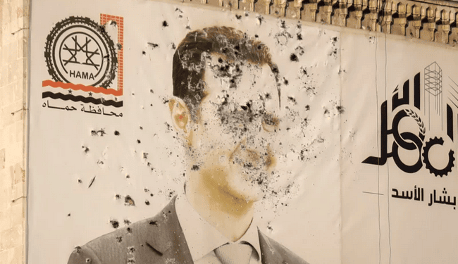 An image of Syrian President Bashar Assad, riddled with bullets, is seen on the facade of the provincial government office in the aftermath of the opposition's takeover of Hama, Syria, Friday, Dec. 6, 2024. Omar Albam/AP/AP