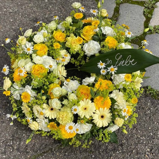 moderne trauerfloristik urne kranz aus Pfaffenhofen mit gelben Rosen und Gerbera von Gerti Haslauer