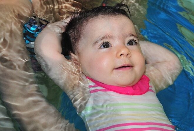 baby is learning back floating in water in a swimming lesson