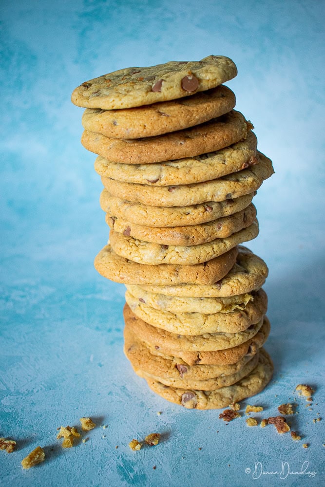 Big stack of cookies on blue background, crumbs at bottom