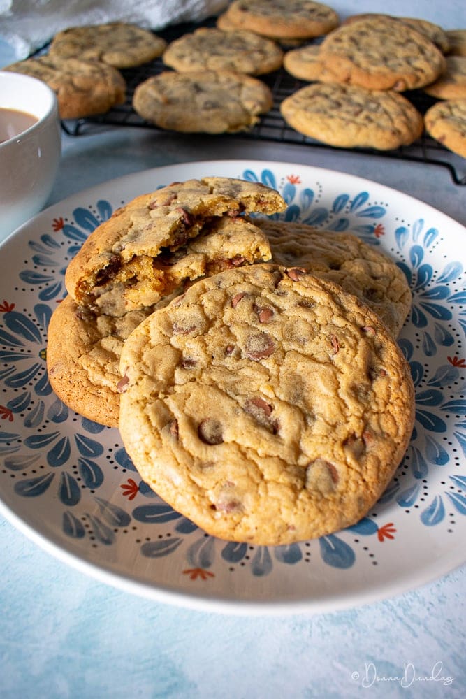 Chewy cookies on patterned plate, more cooling on wire rack in the background