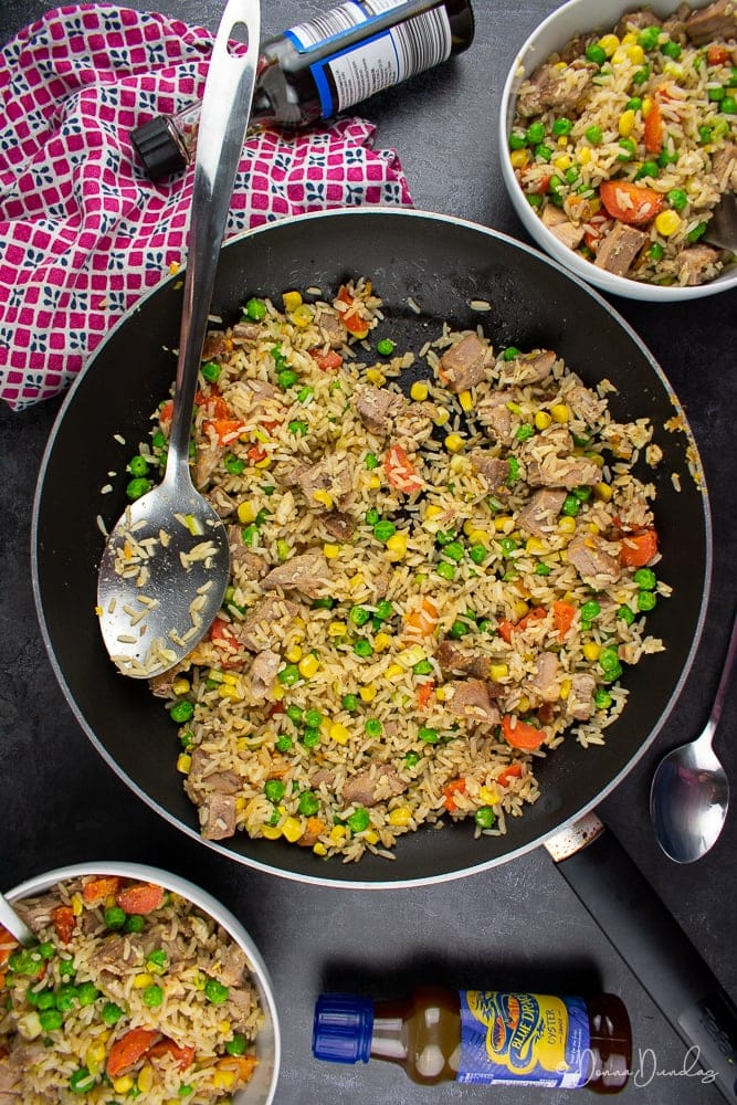 top view of fried rice with pork and veg in frying pan, served portions to the sides.