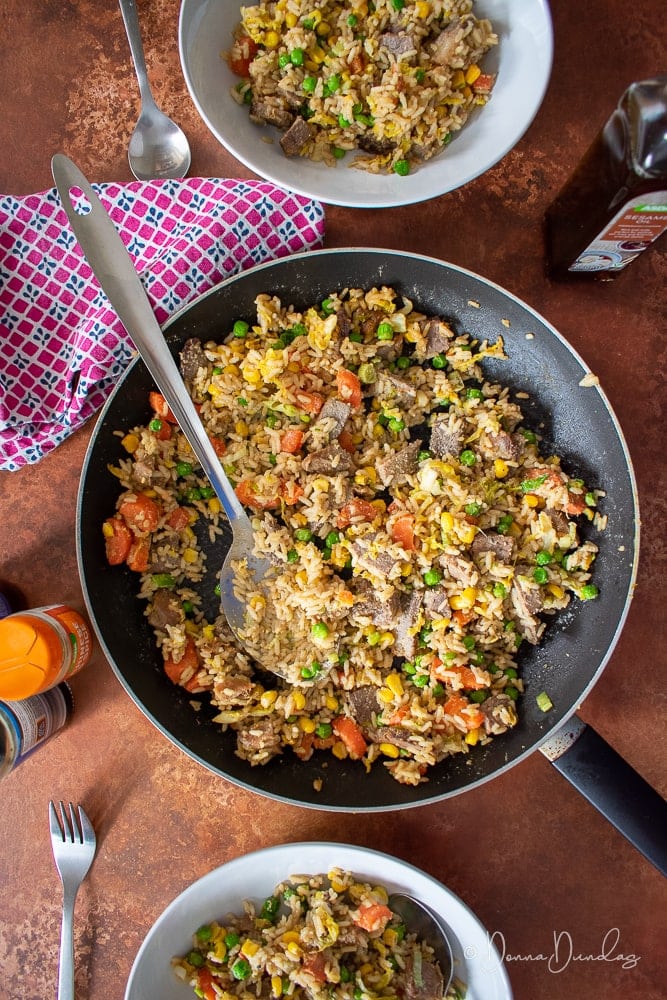 Beef and Vegetable Fried rice in frying pan, 2 served portions in bowls.