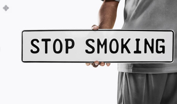 A person holding a Stop smoking sign.