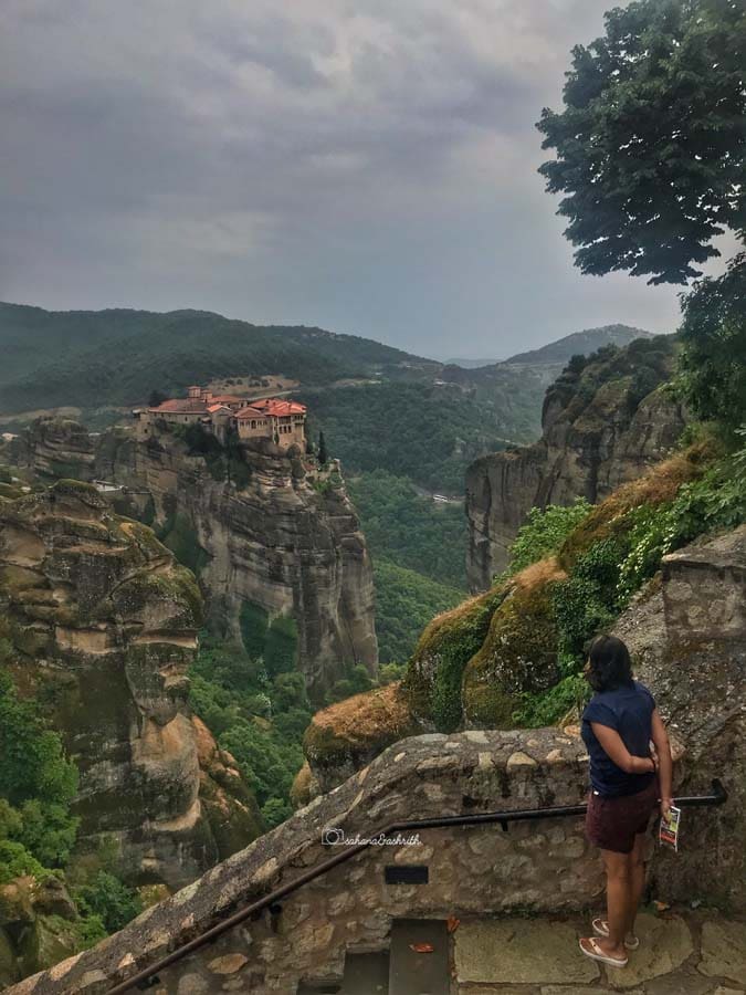 Indian woman traveller wearing slippers gazing at the hilltop monastery in Meteora