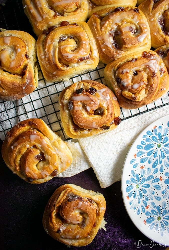 top view of mince and marzipan Chelsea buns on wire rack, 2 on side, plate leaving shot