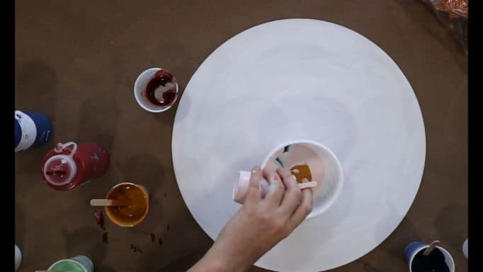 pouring paint in cup on top of primed wood round